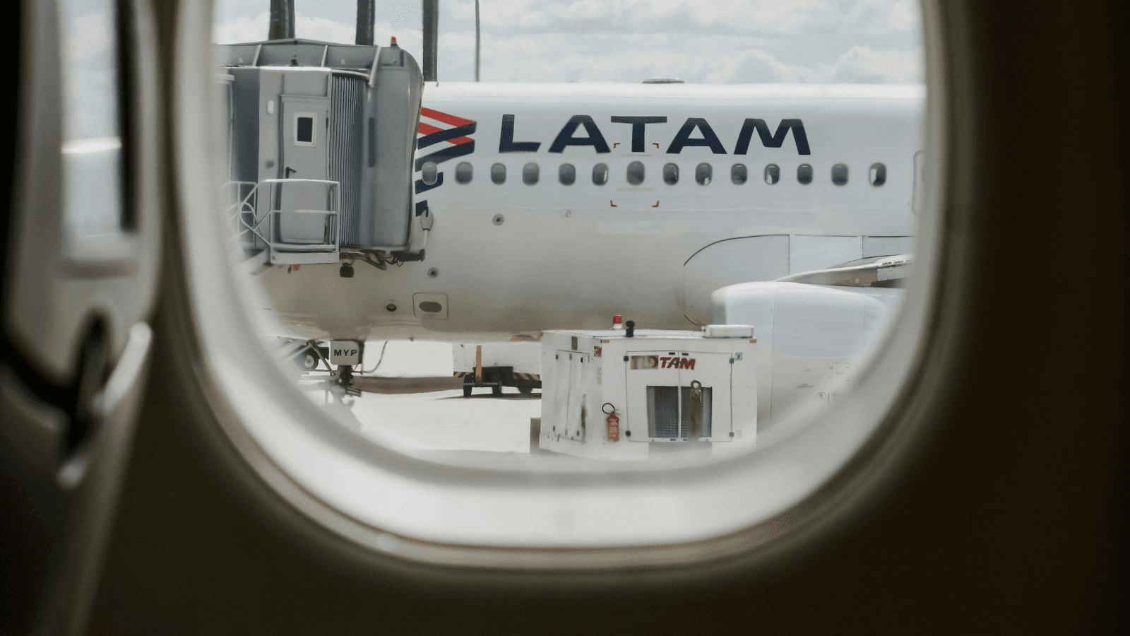 Avião da LATAM visto pela janela de outra aeronave em aeroporto brasileiro